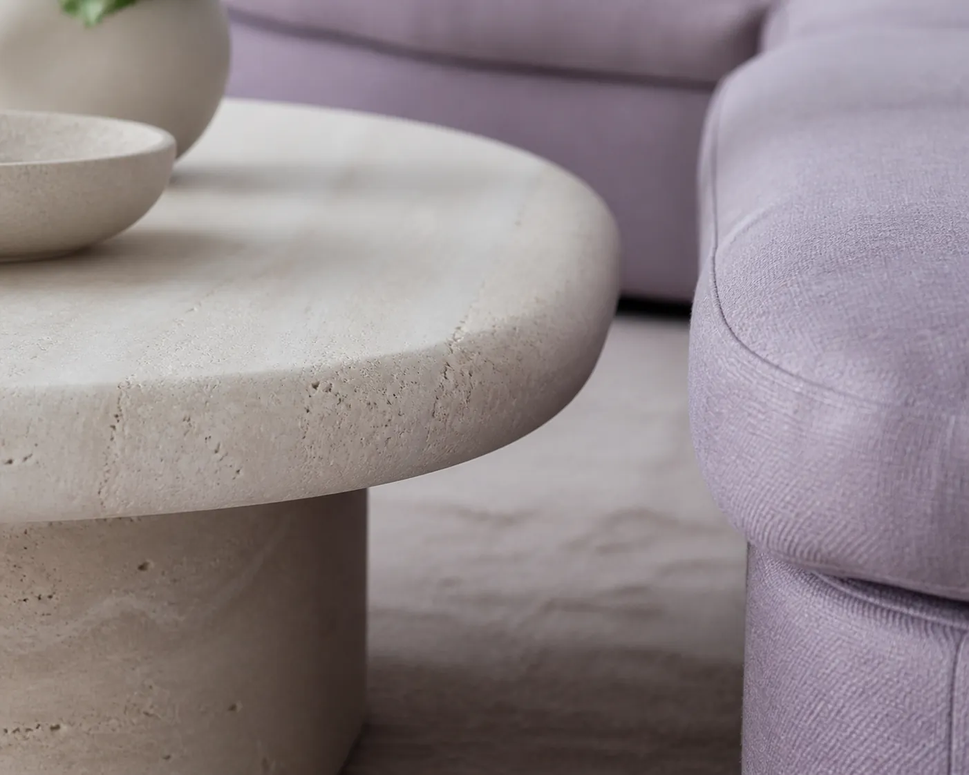 Rounded stone coffee table edge beside a sofa seat