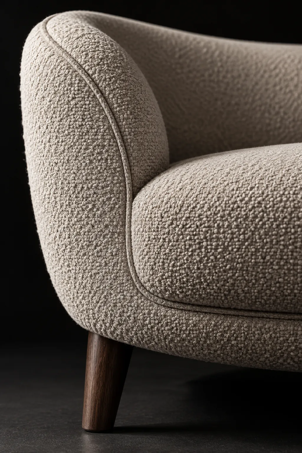 Close detail of tailored curved-sofa upholstery and walnut leg